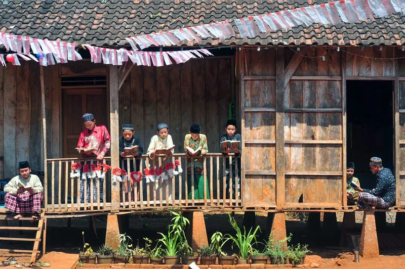 Anak-anak membaca di beranda rumah kayu
