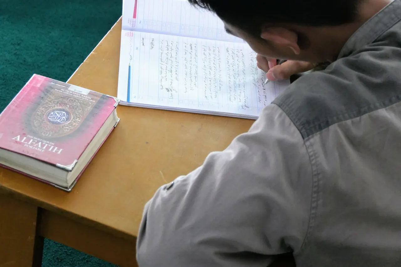 Santri menulis catatan di samping kitab